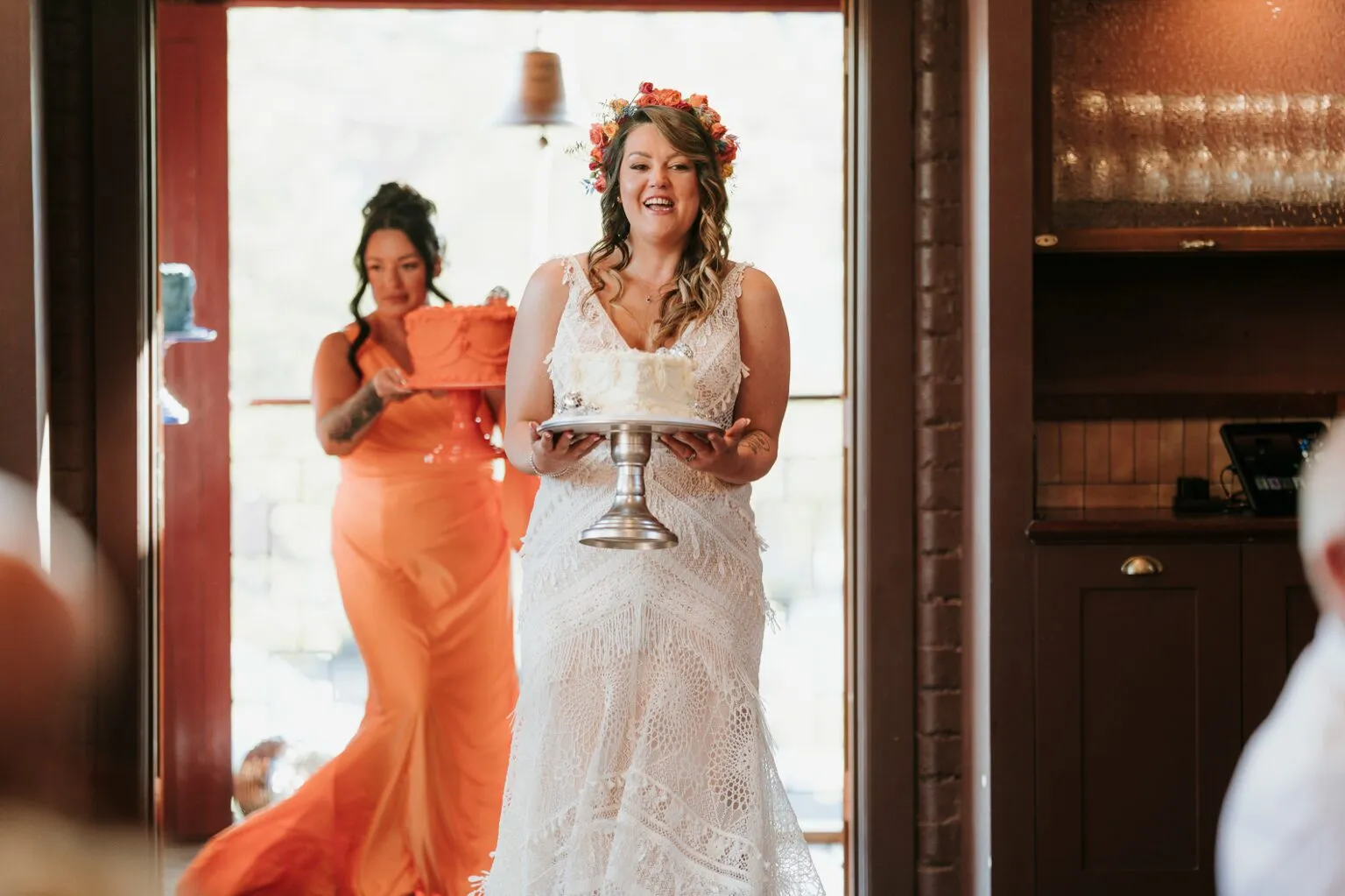 Bride carrying her white Cherry Bakewell wedding cake into the room