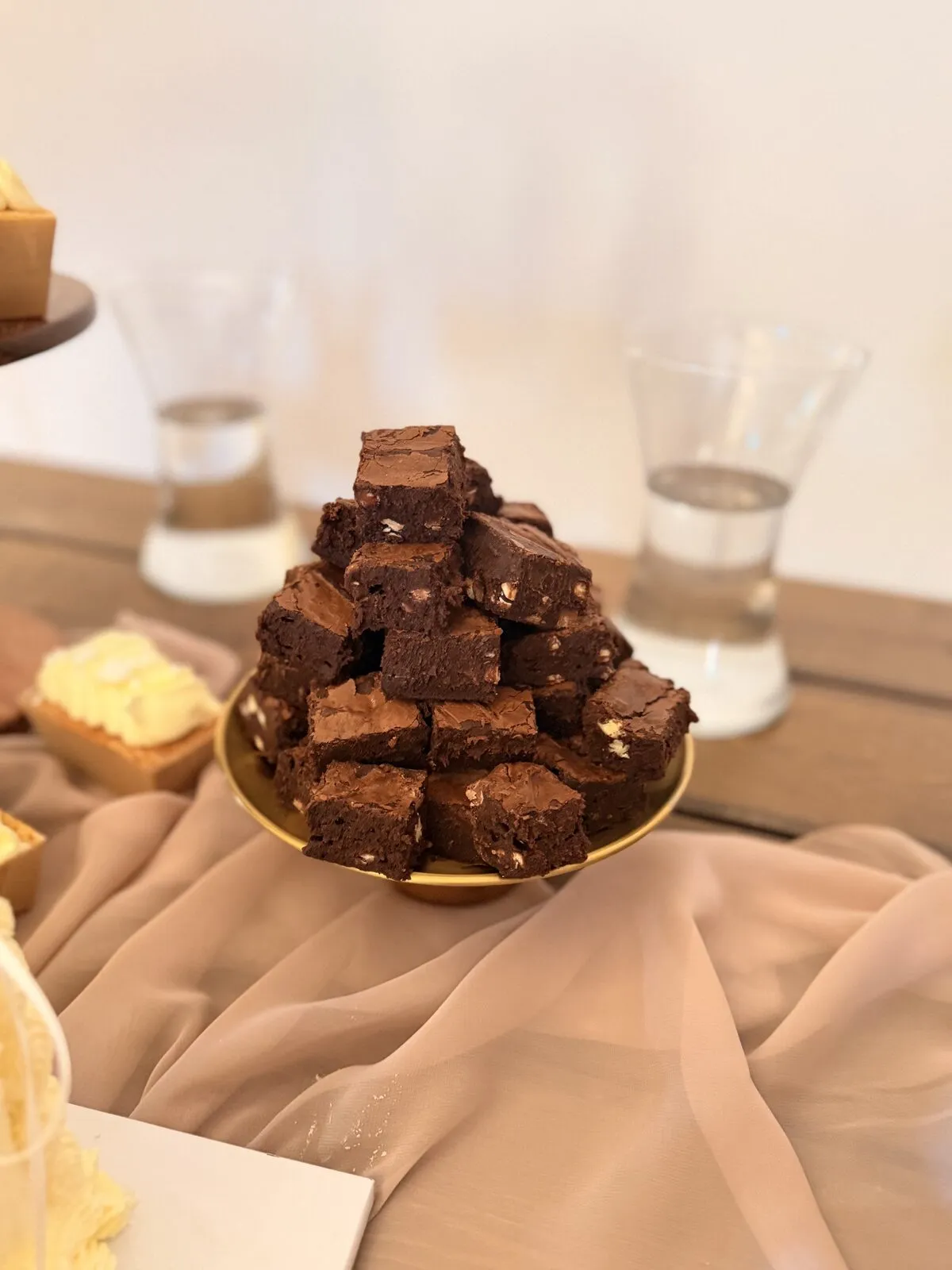 A stack of brownies styled on a gold plate on a wedding dessert table