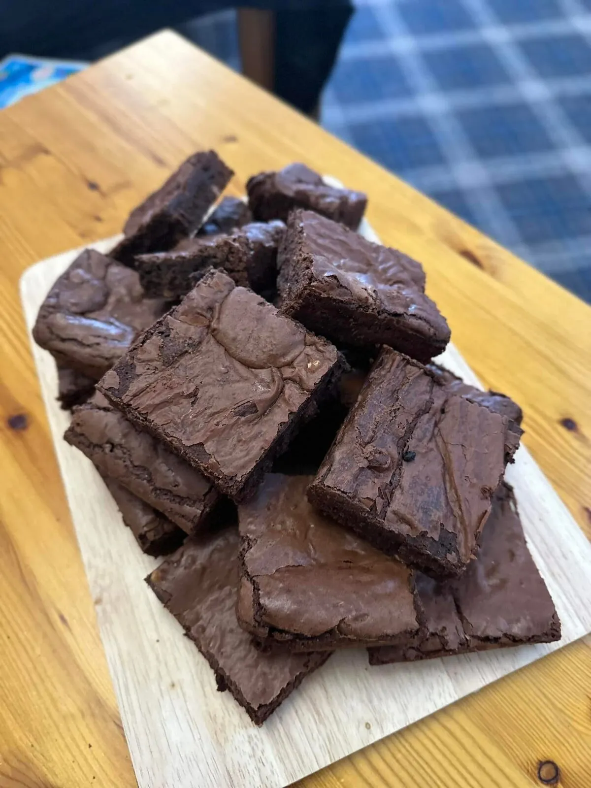 A rustic pile of rich, fudgy chocolate brownies on a wooden board