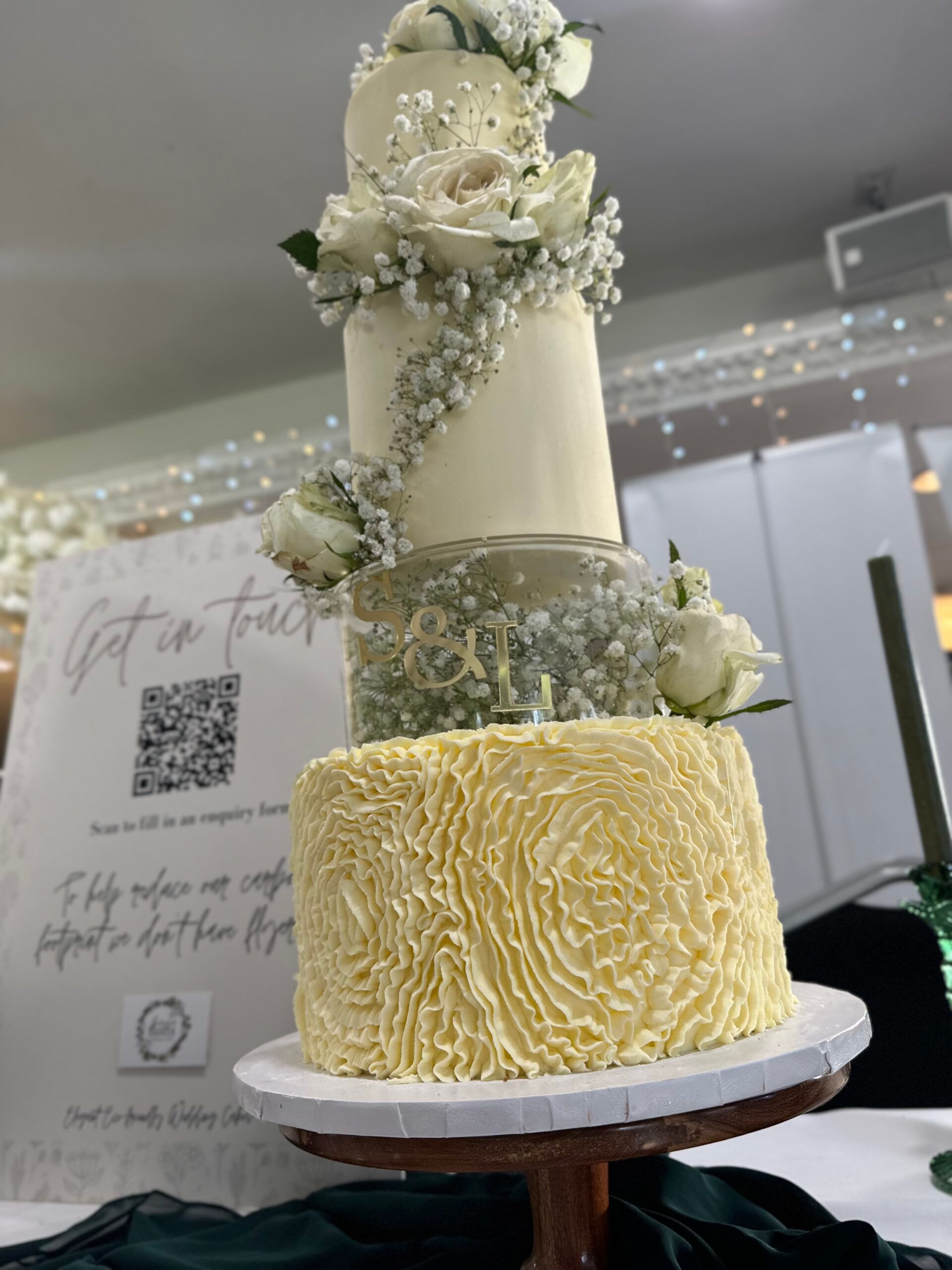 Elegant tiered wedding cake finished with white roses and gypsophila