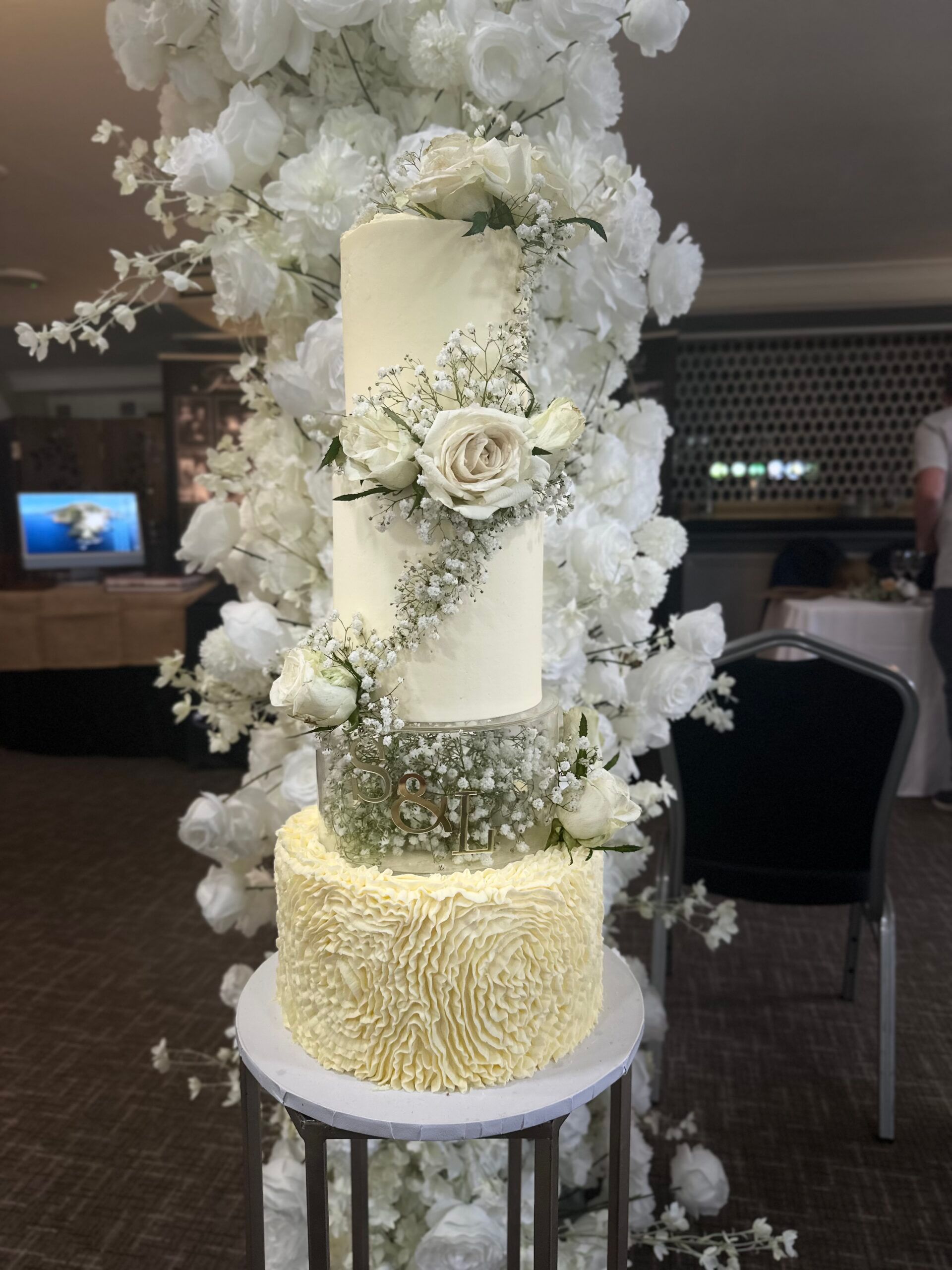 Tall ivory wedding cake with a cascade of white blossom