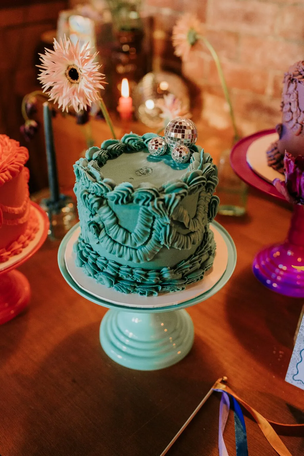 Teal Raspberry and Pistachio Lambeth wedding cake with intricate piping and a pink gerbera