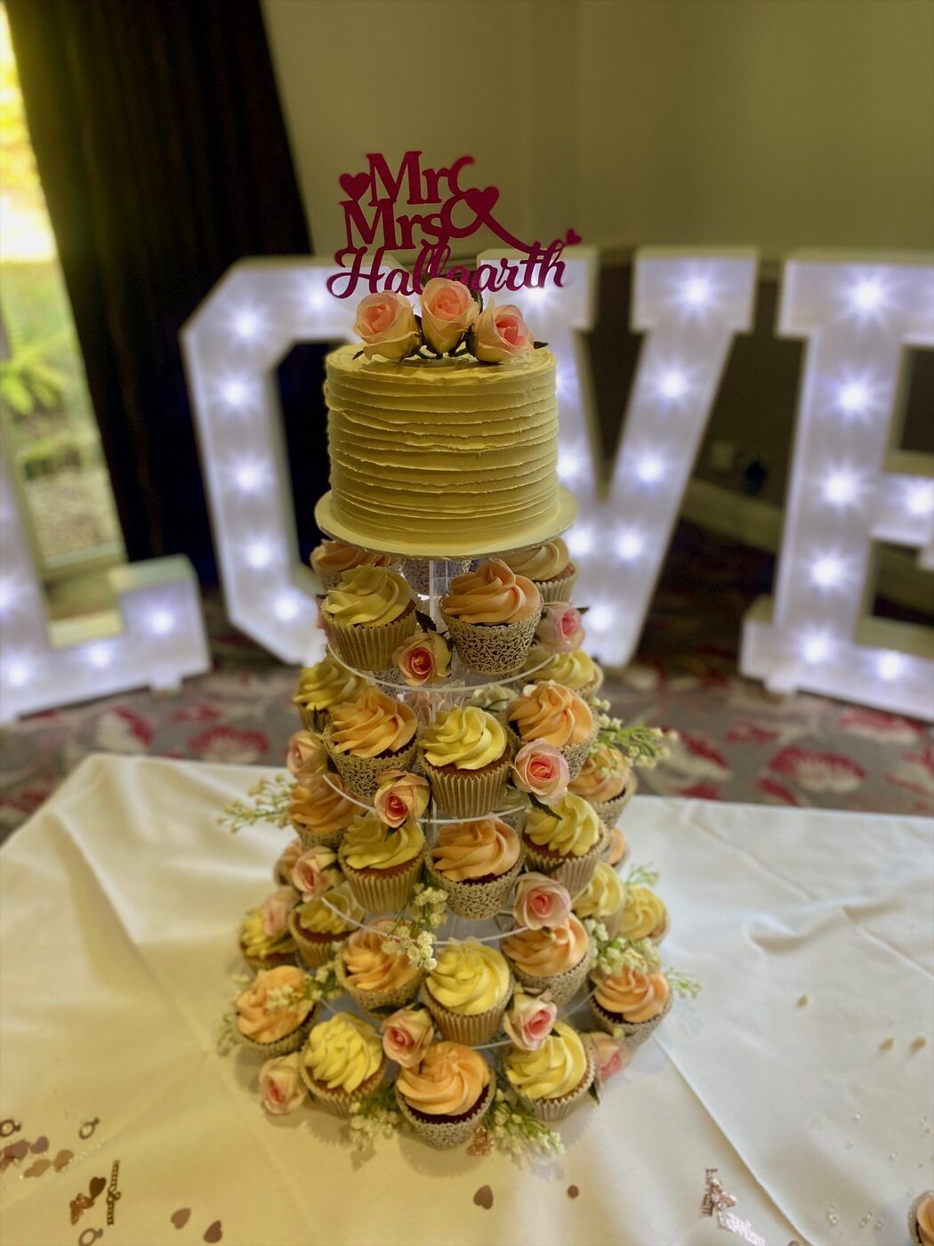 Wedding cupcake tower with a cutting cake on top, surrounded by iced cupcakes