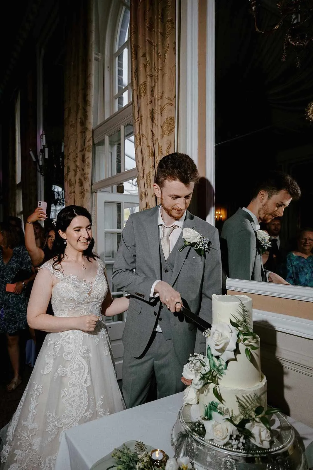 Adam and Elisabeth cutting their green and white wedding cake at Ringwood Hall