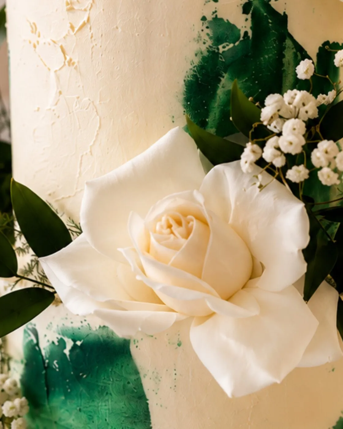 Close-up of a white rose and gypsophila against the green brushstroke buttercream texture