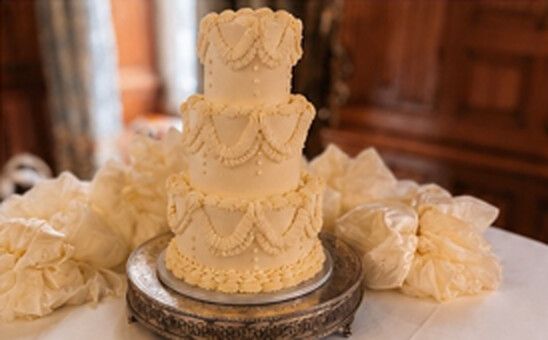 Three tier vintage Lambeth-piped wedding cake with buttercream swags on a silver stand